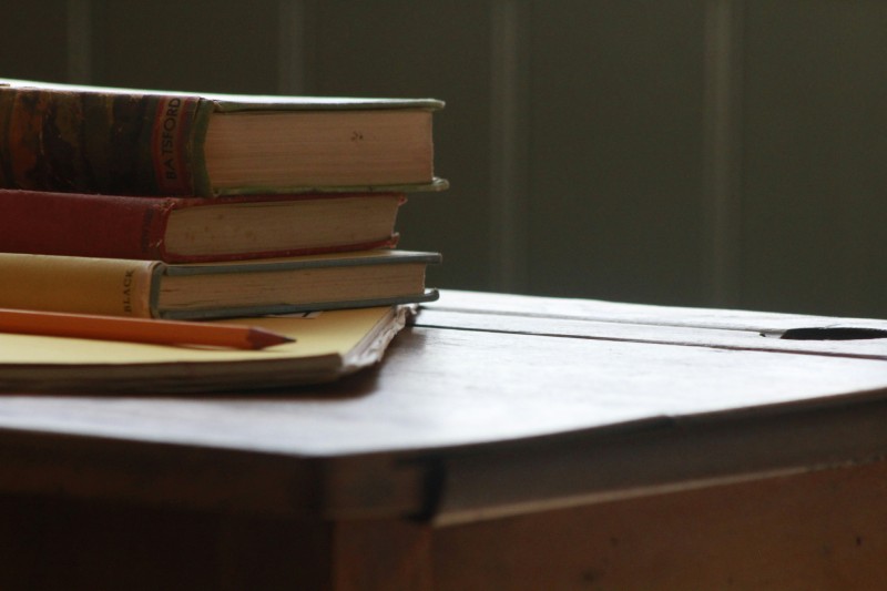Олівець та кілька книг на дерев'яному столі — образ письма, підготовки та навчання
